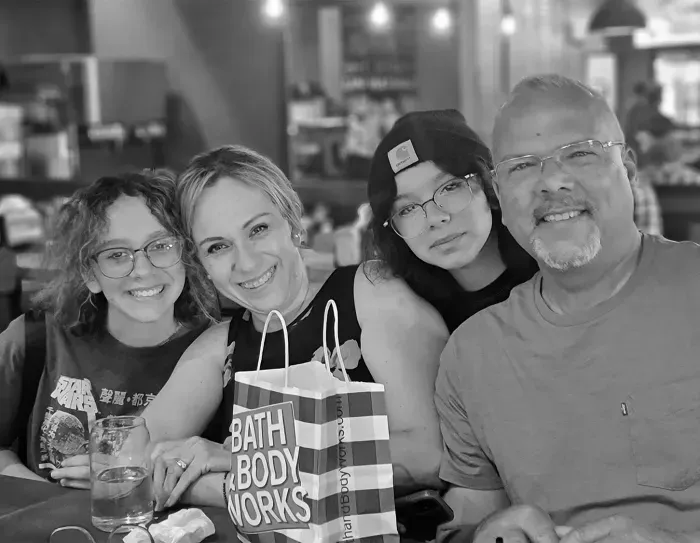 Copa Mechanic owner and his family smiling at a restaurant with a shopping bag.